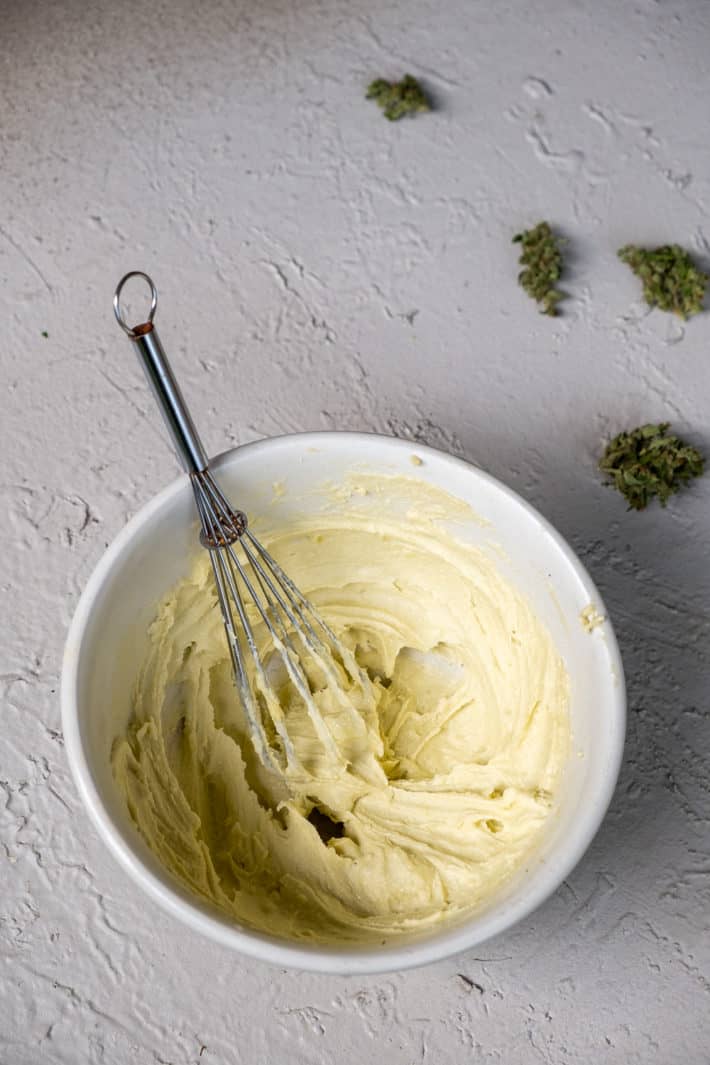 Whipped cannabutter in an ironstone bowl with a whisk still in it.