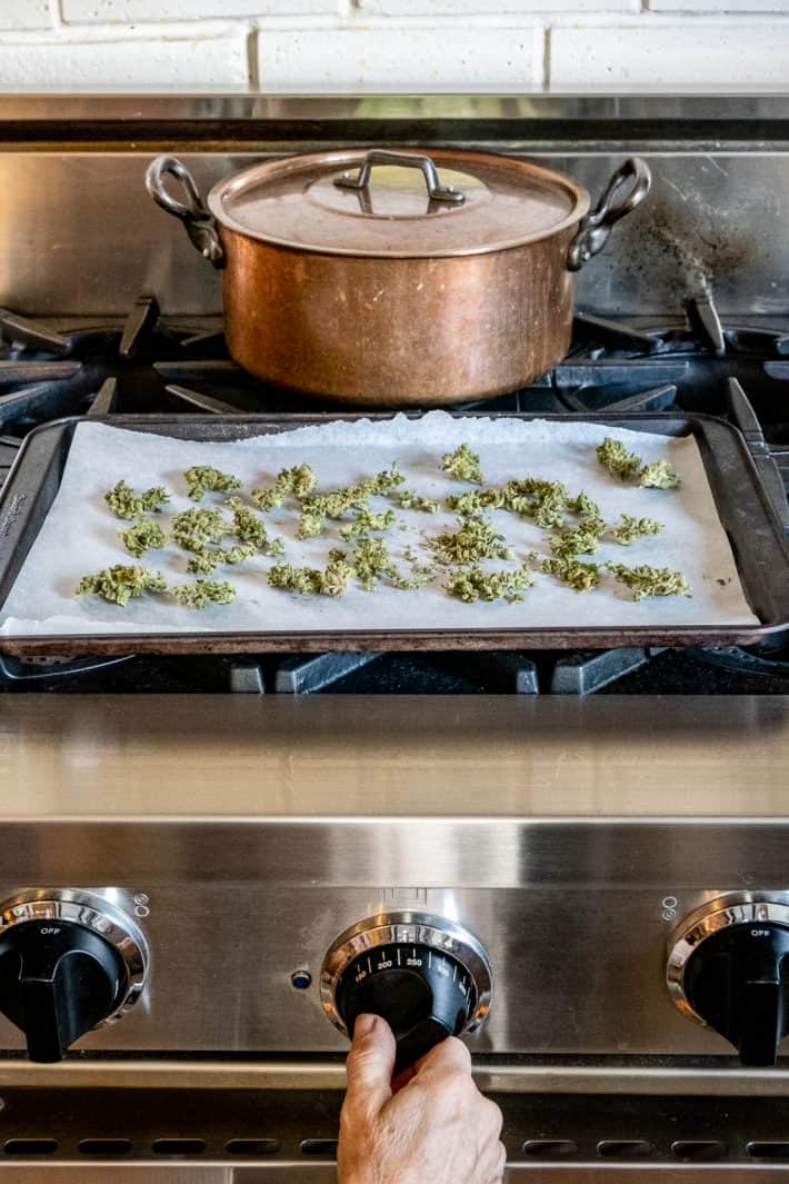 Oven knob on Blue Star oven being set to 140 degrees, with pan of cannabis ready to decarb on top.