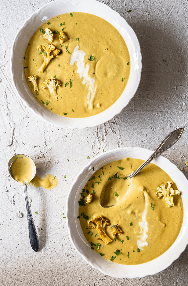 Curried cauliflower soup from above in ironstone bowls topped with slices of cauliflower and swirls of yogurt.