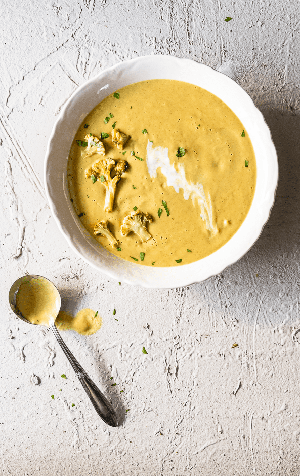 Colourful cauliflower soup in an ironstone bowl topped with sliced roasted cauliflower, coriander and a swirl of yogurt.