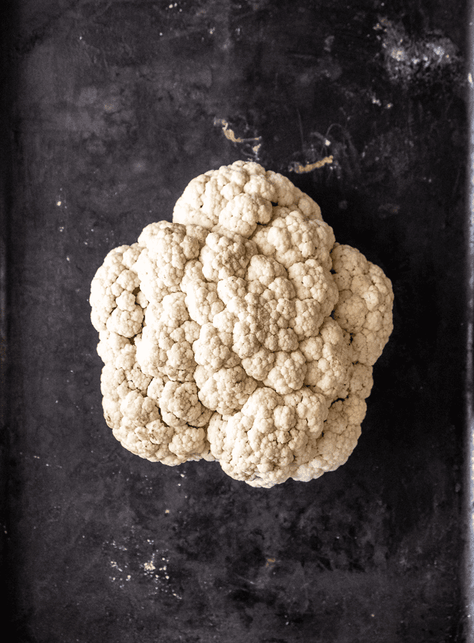 A head of cauliflower on a mottled black background.