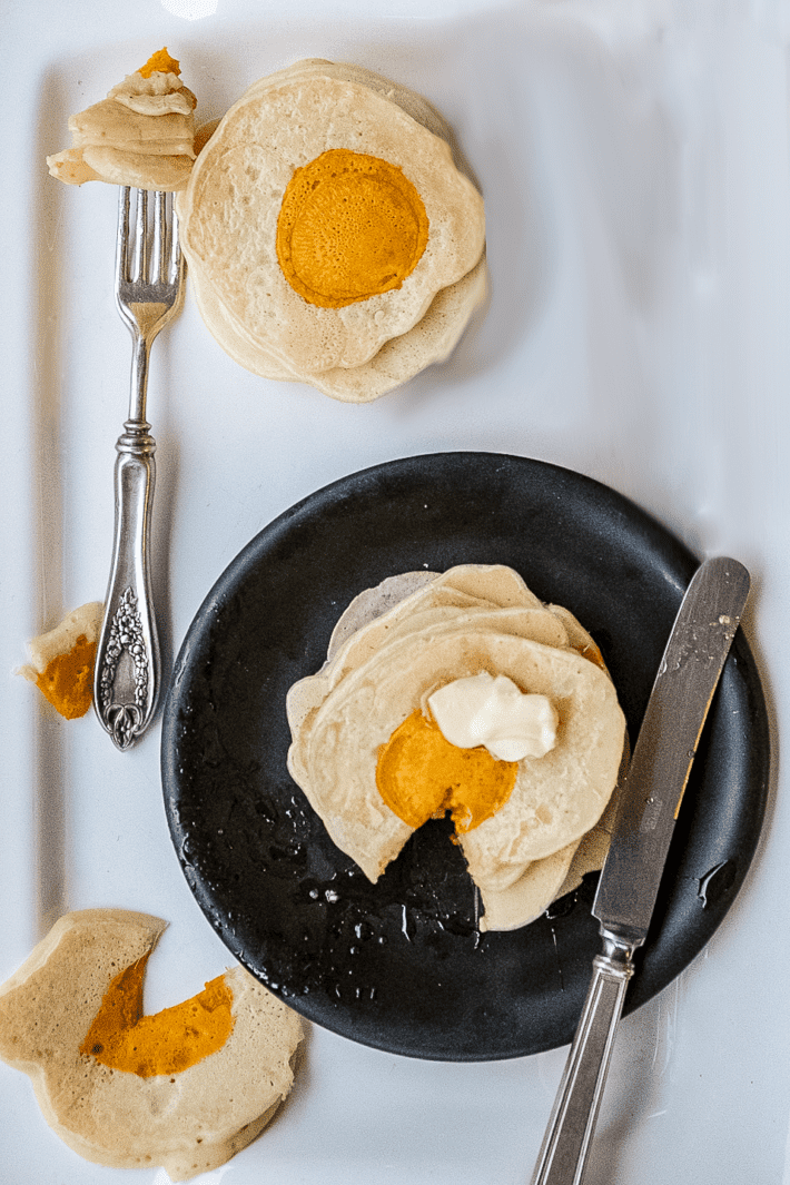 Stack of pancakes that look like eggs with butter and syrup.