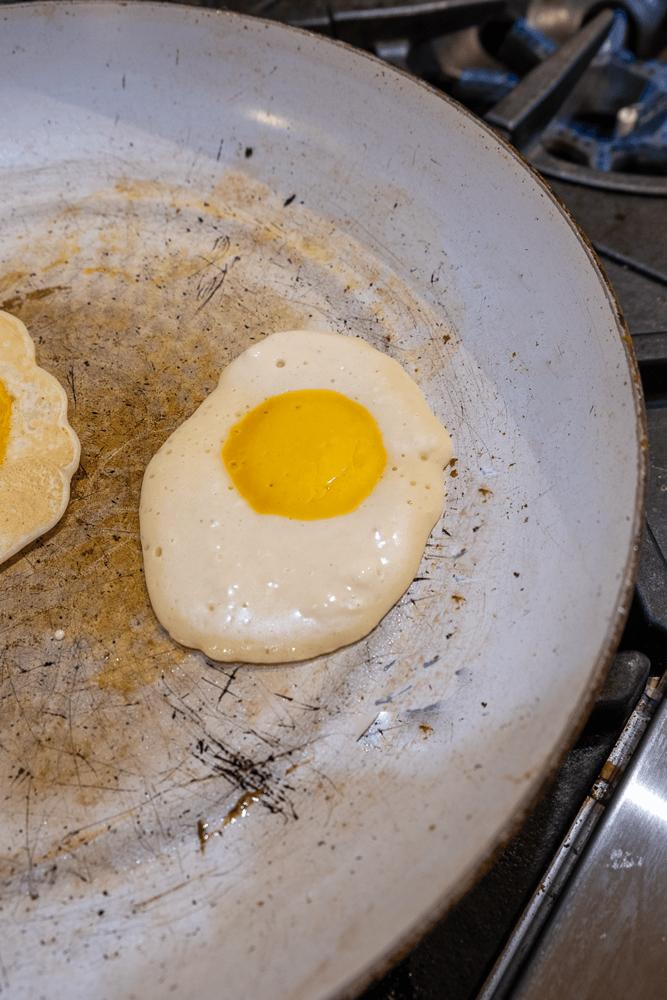 Pancake that looks like egg cooking in non stick pan.