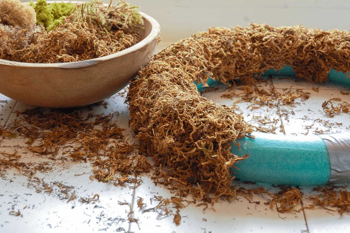 Hot gluing moss to pool noodle wreath form