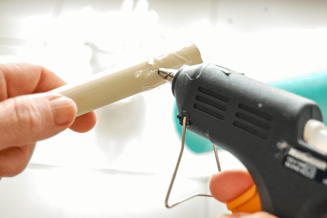 Adding hot glue to PVC pipe.