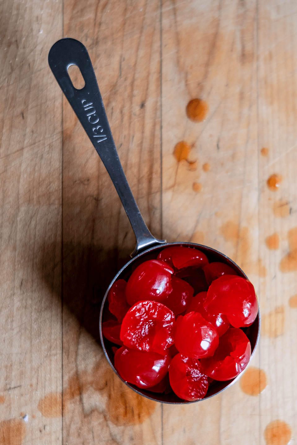 Maraschino cherries in a measuring cup.