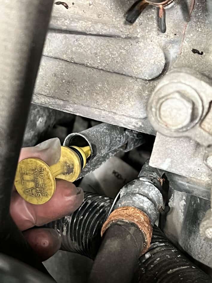 Pulling yellow automatic transmission fluid dipstick out.