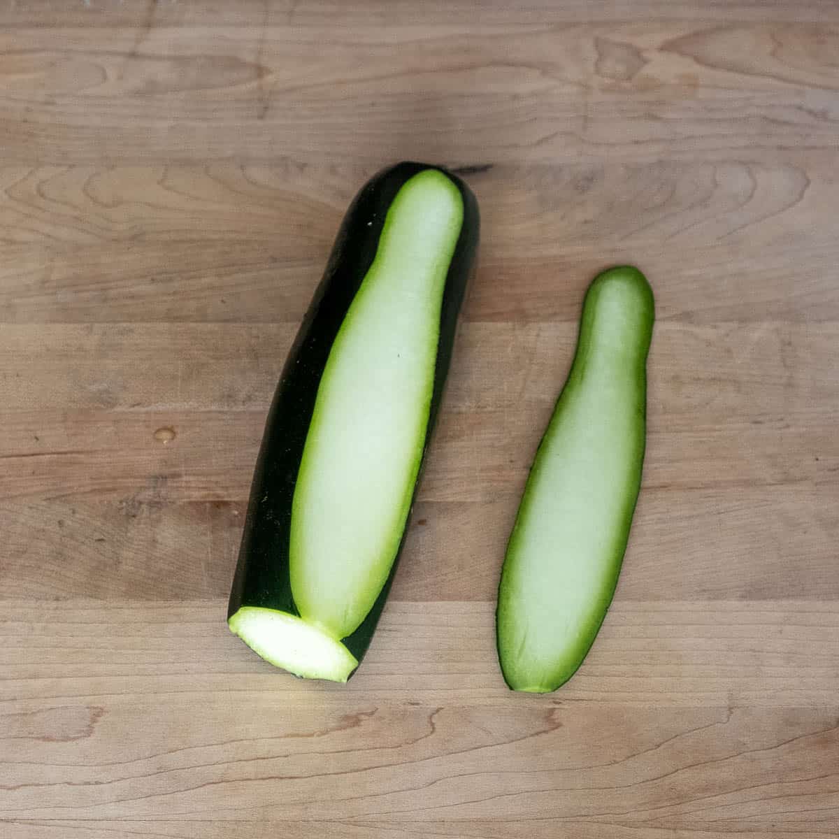 Zucchini with one strip cut off of it lengthwise.