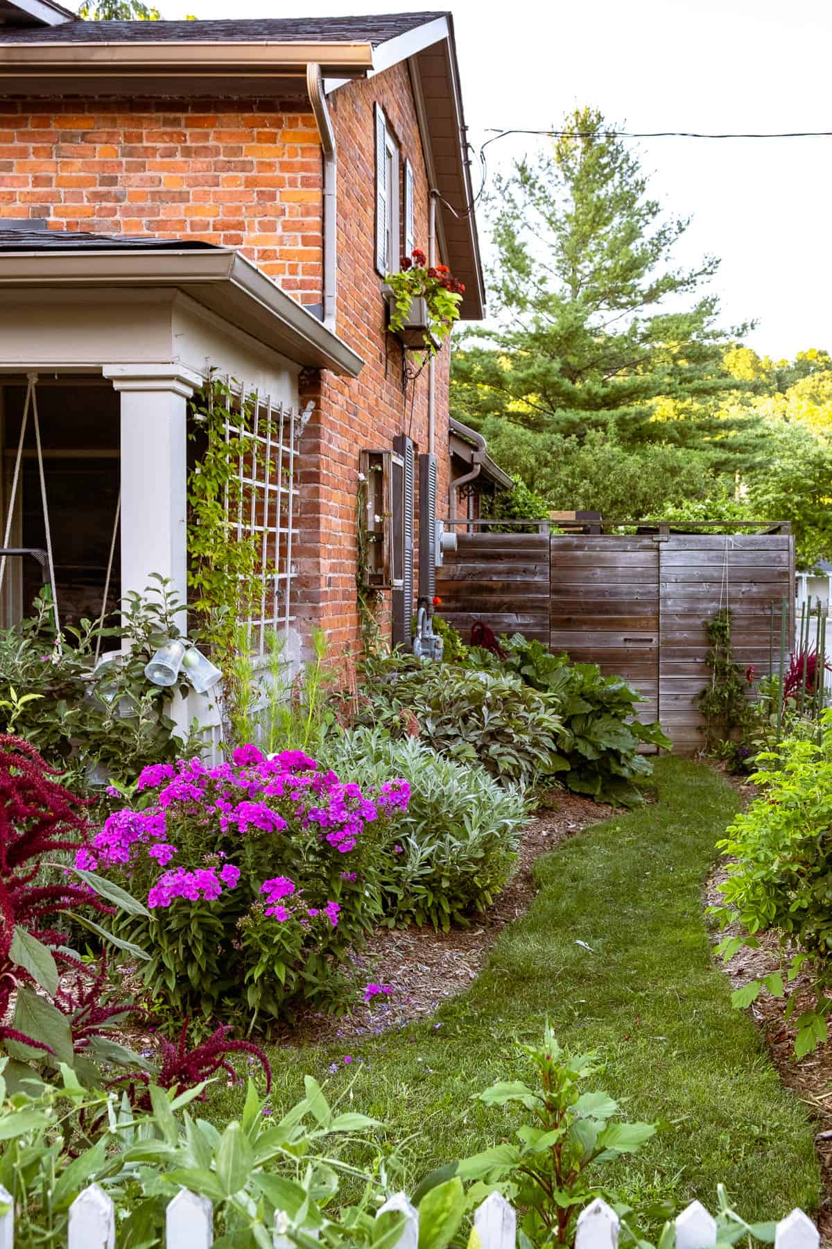 Side of brick cottage with english cottage garden type pathway in bloom.