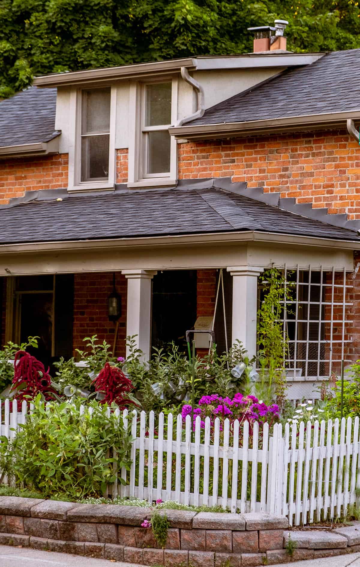 Brick century workers cottage surrounded by picket fence and english style garden.