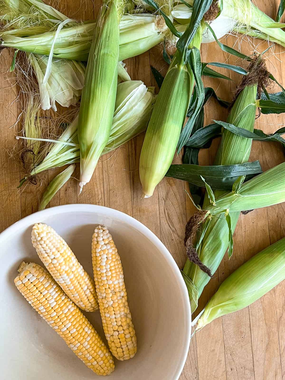 Fresh, just picked corn laid out on butcher block countertop.