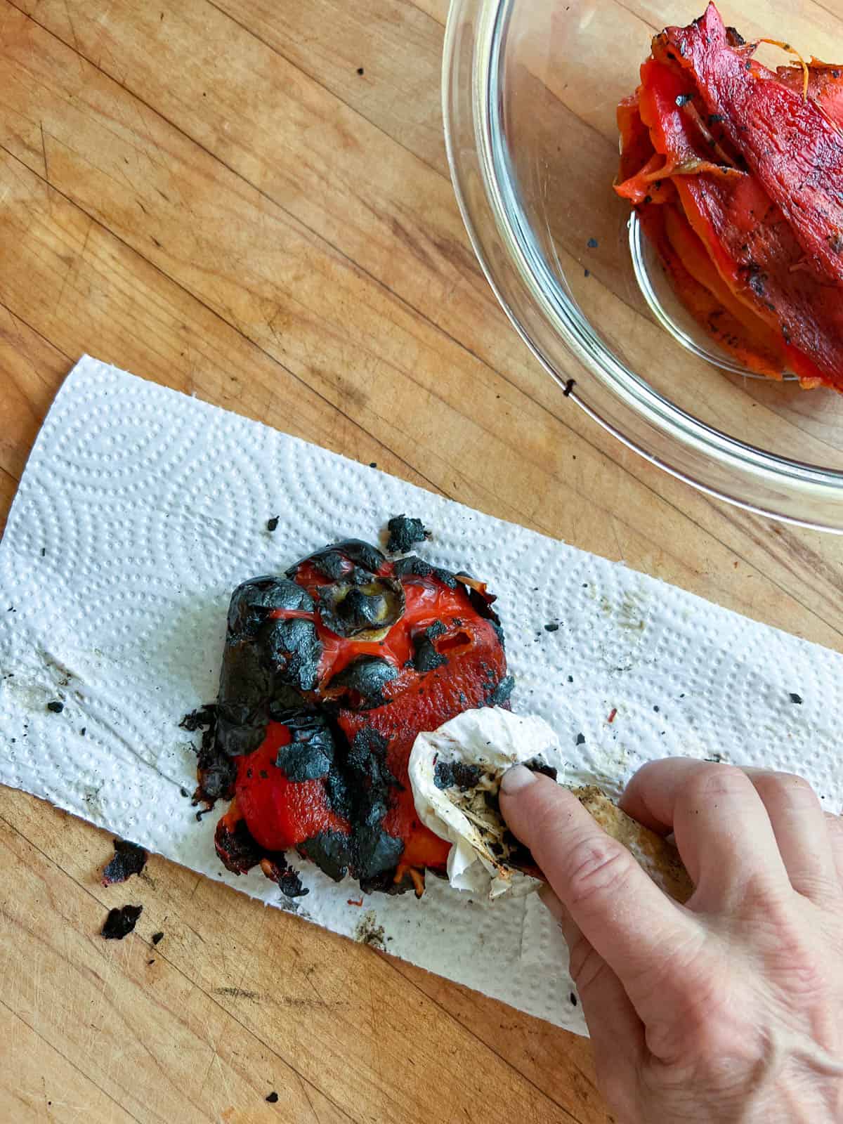 Wiping charred skin off of red pepper with a paper towel.