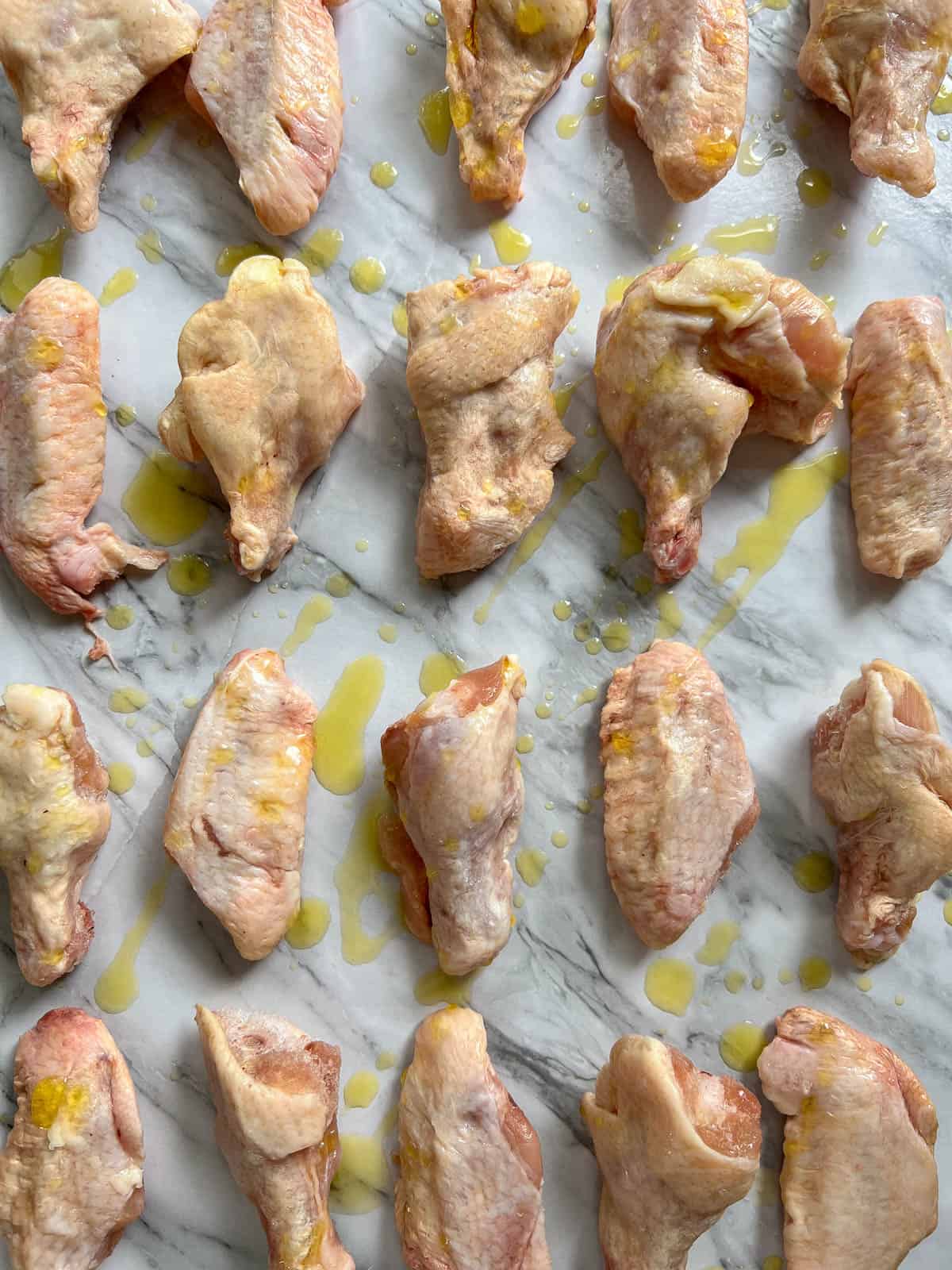 Raw chicken wings drizzled with oil.