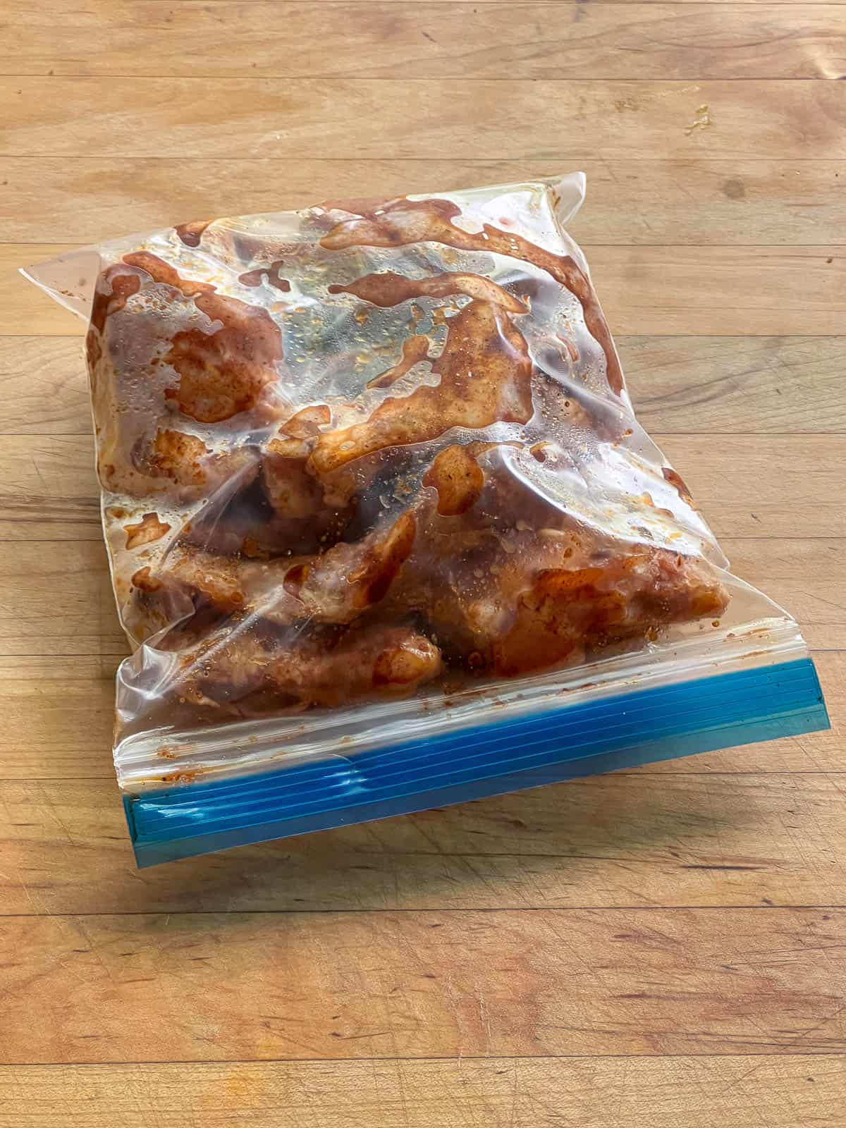 Raw chicken wings marinating in plastic bags.