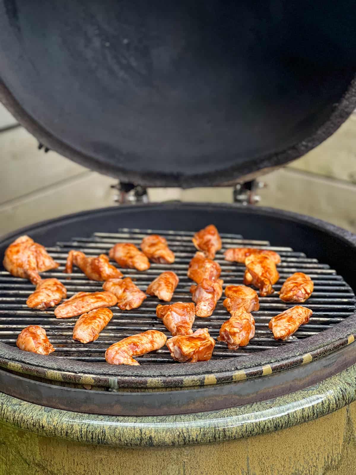 Raw chicken wings with dry rub marinate on smoker grill.