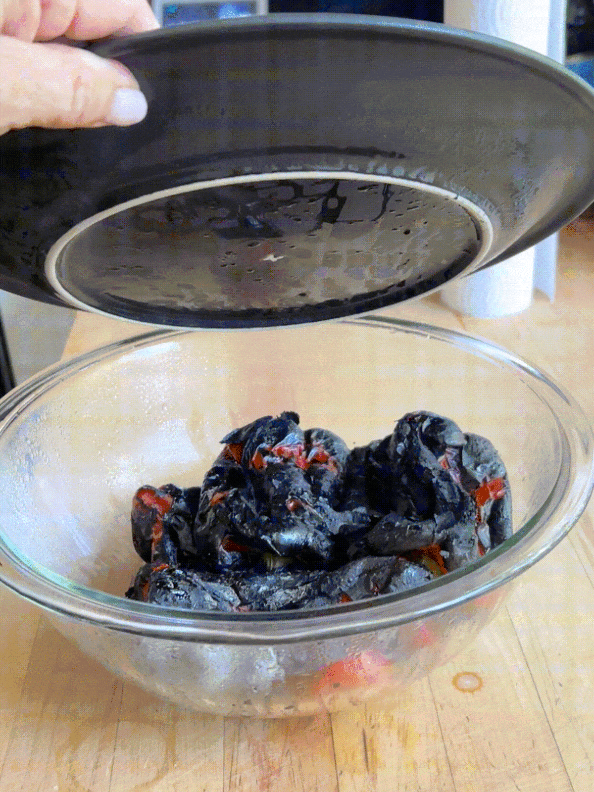 Steam rising from bowl full of charred red peppers.