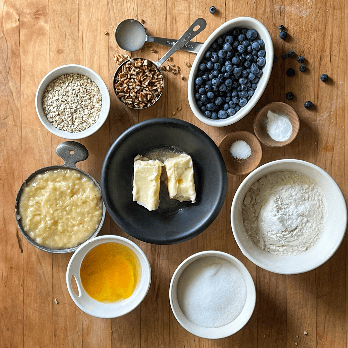Ingredients for blueberry banana bread laid on wood countertop.