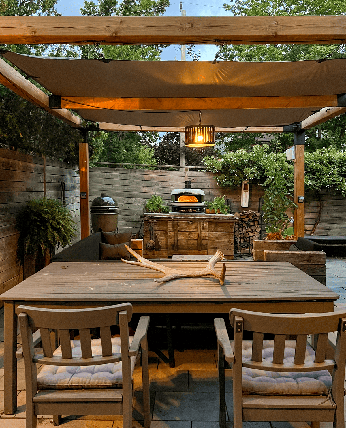 Outdoor dining area with pergola and pizza oven.