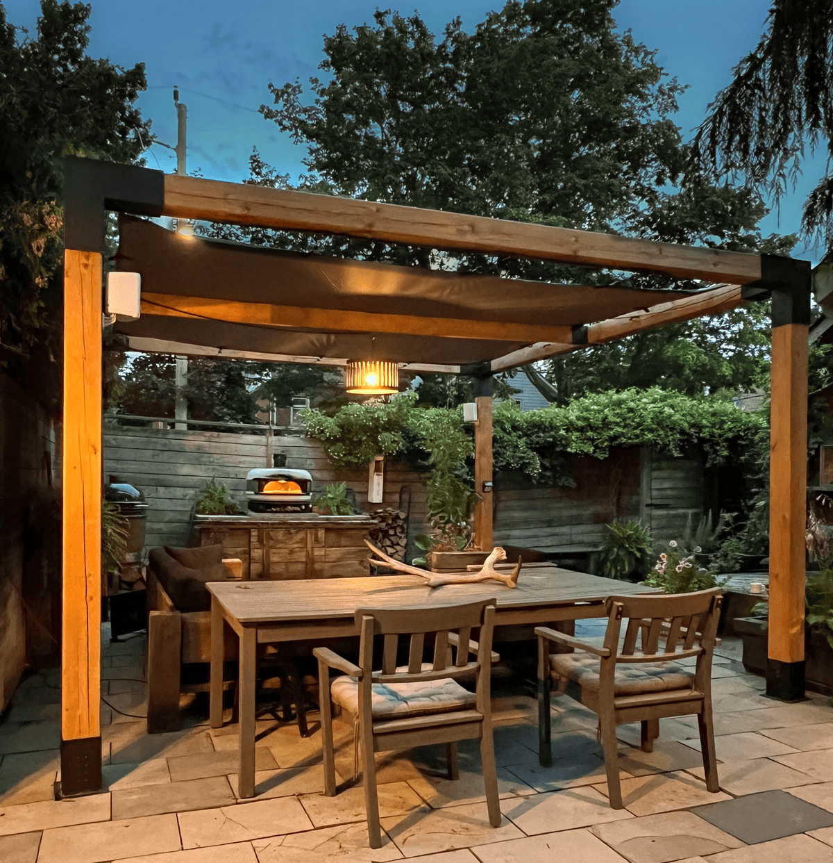 Backyard pergola with dining table, sectional and Gozney pizza oven.