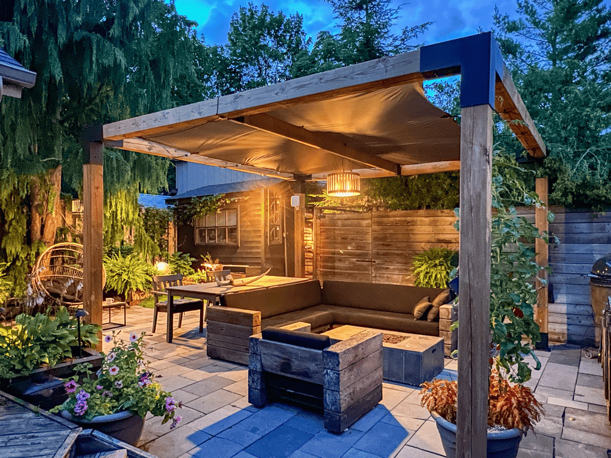 Pergola in backyard at night with lighting.