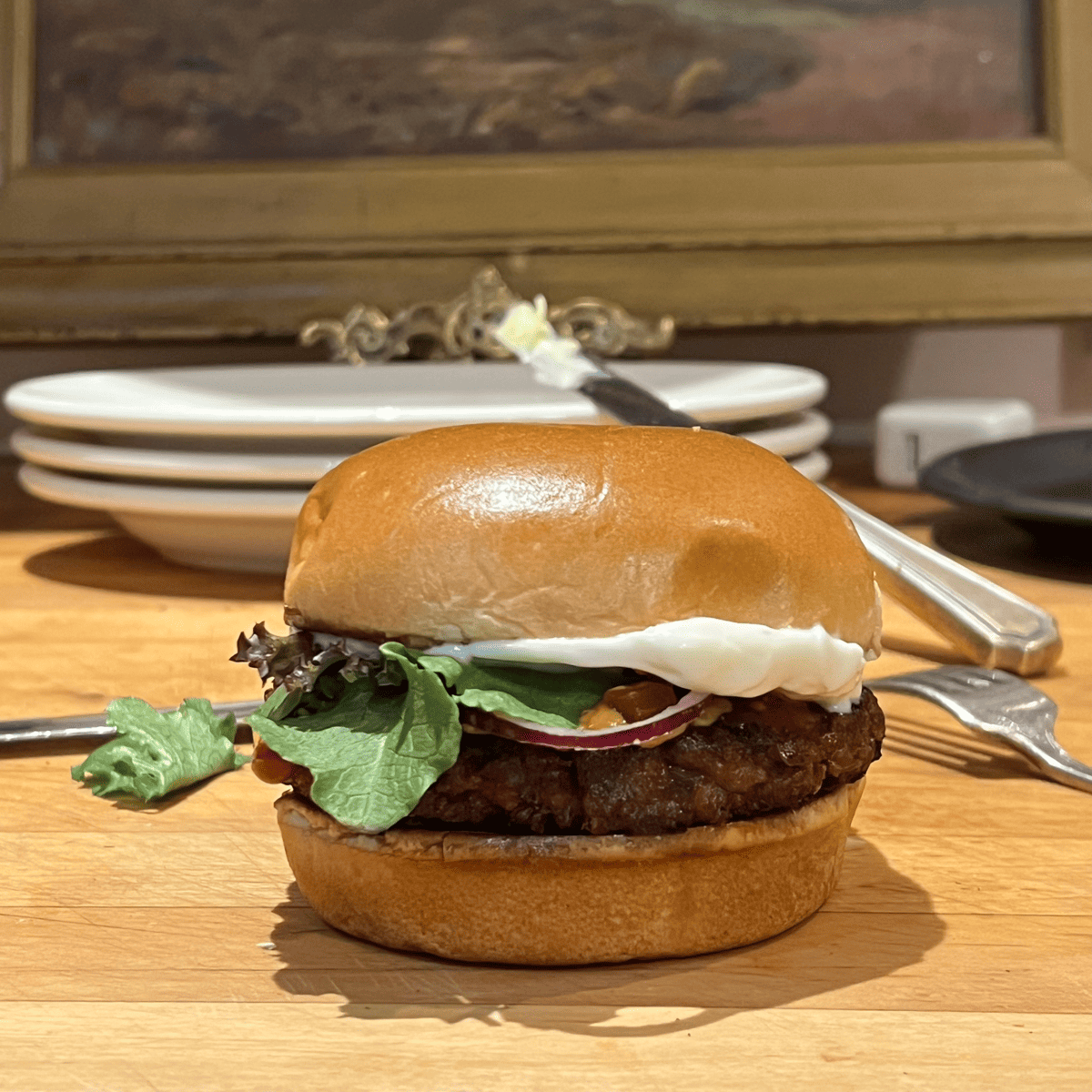A loaded plant based burger on a butcher block countertop.