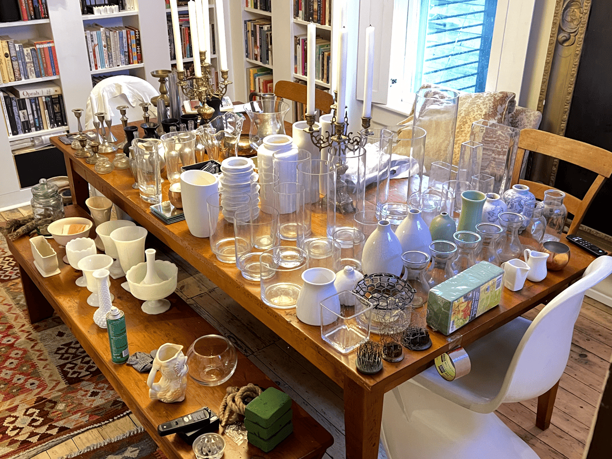 Dining room table filled with extra vases during home organization.