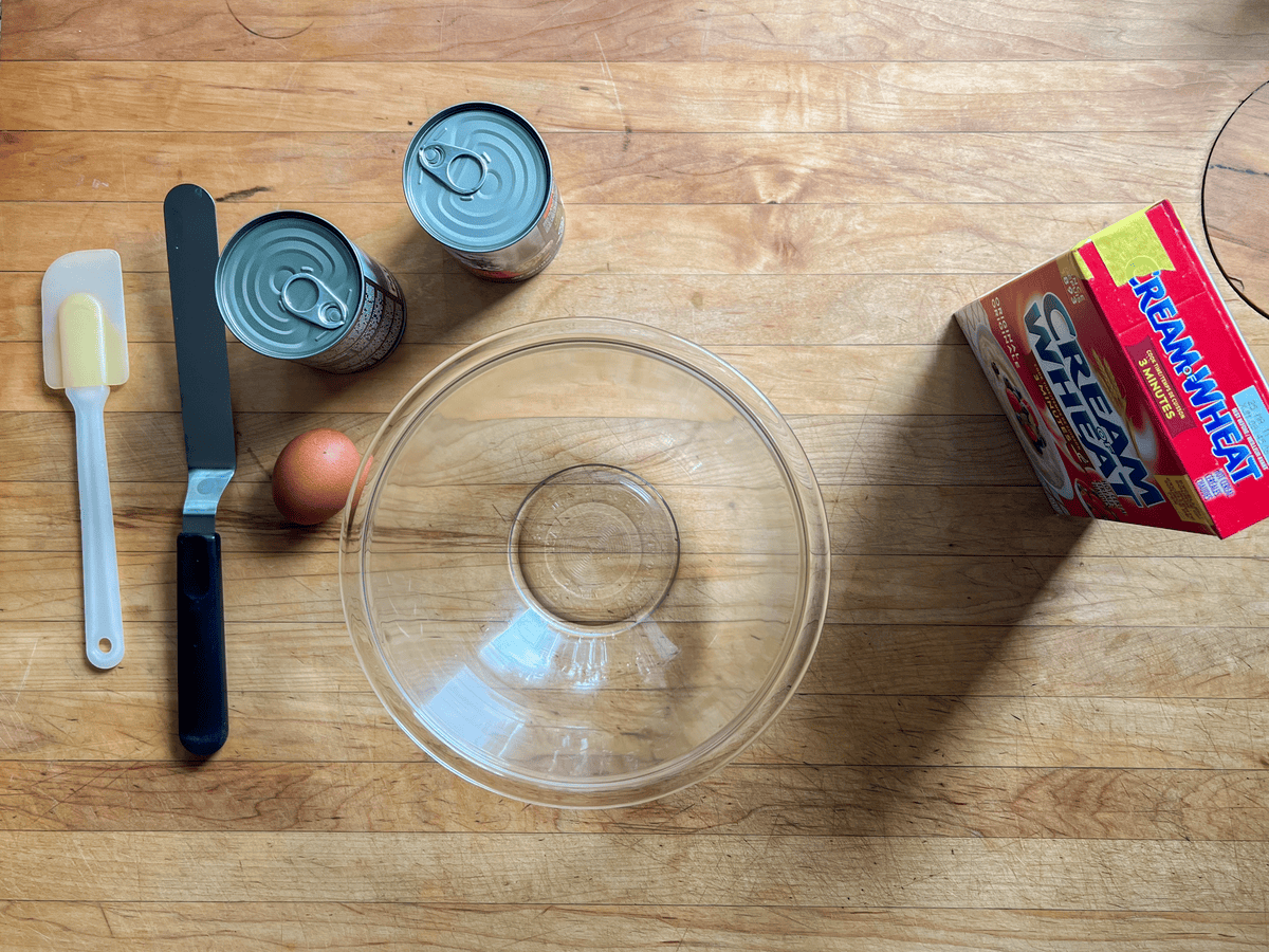 Training treat ingredients including Cream of Wheat, canned dog food and an egg laid on a wood countertop.