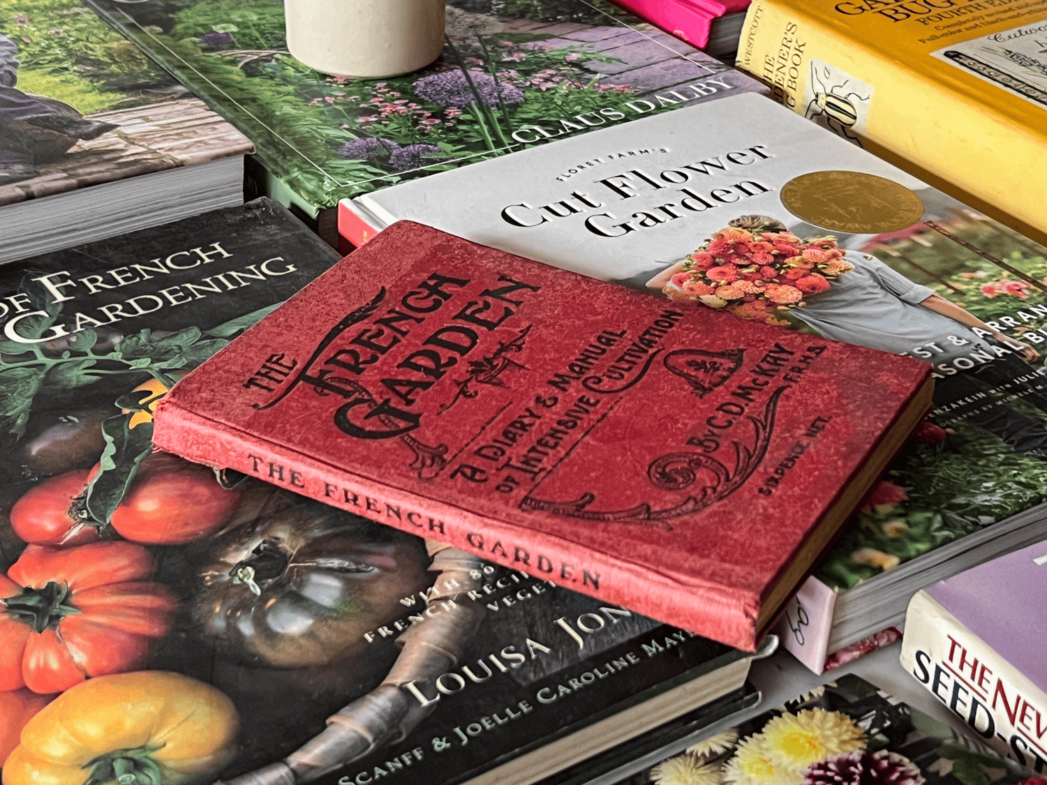 A vintage copy of The French Garden, A Diary & Manual of Intensive Cultivation, with a red hardcover.