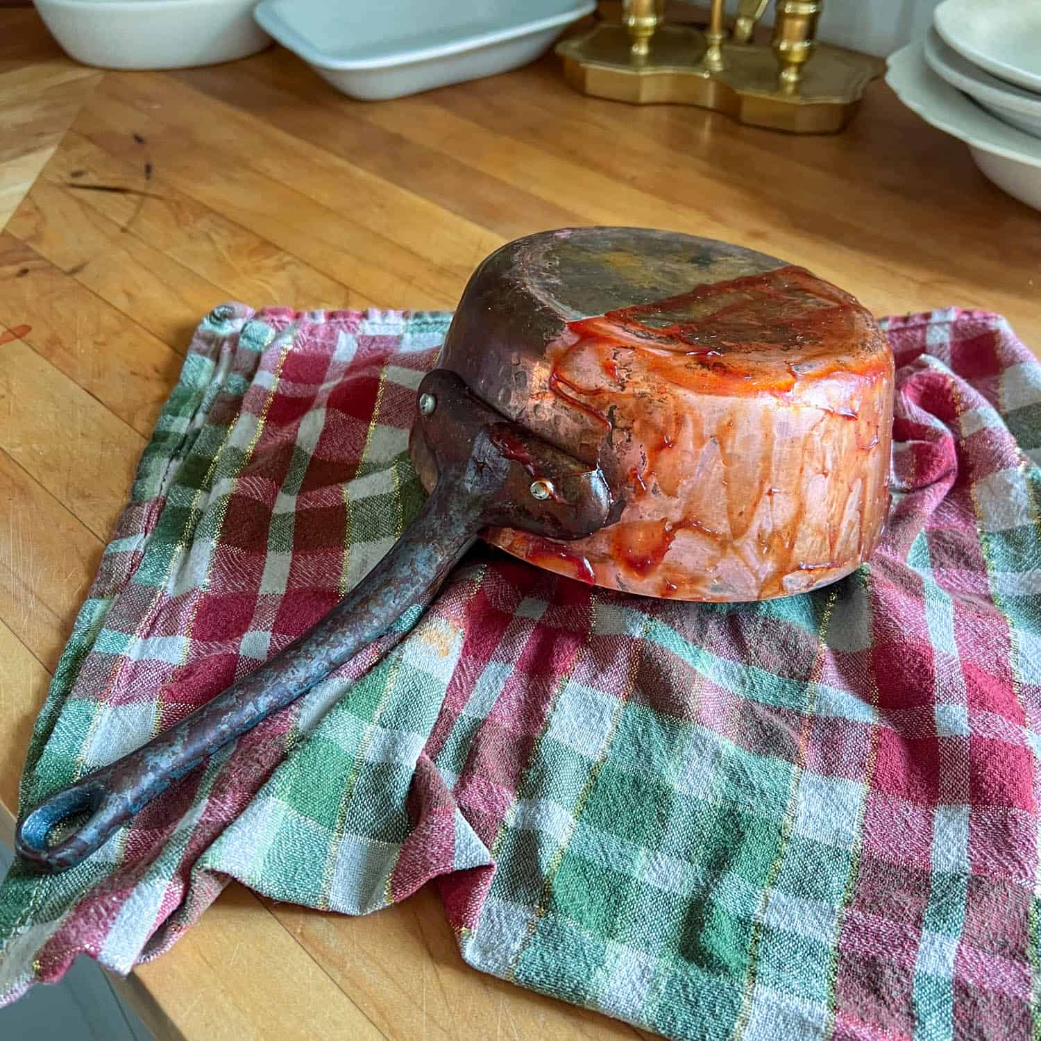 A copper pot on a tea towel being cleaned using the no buff ketchup method.