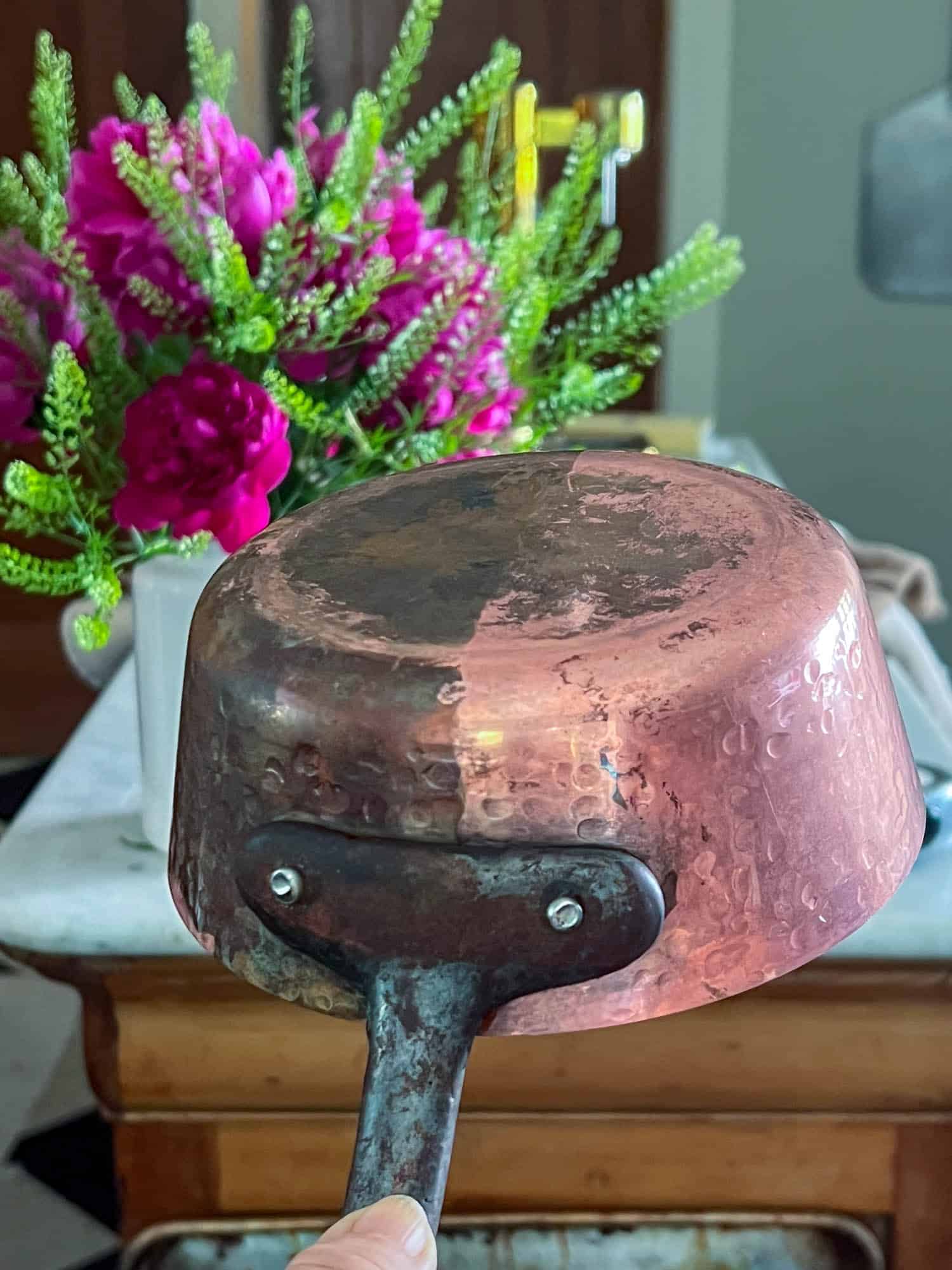 The before and after results of a copper pot cleaned with a no buff ketchup method.