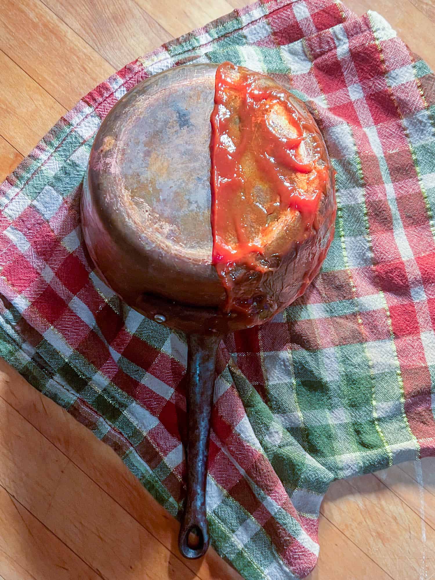 A copper pot cleaning experiment with the ketchup method being used on half of the pot.