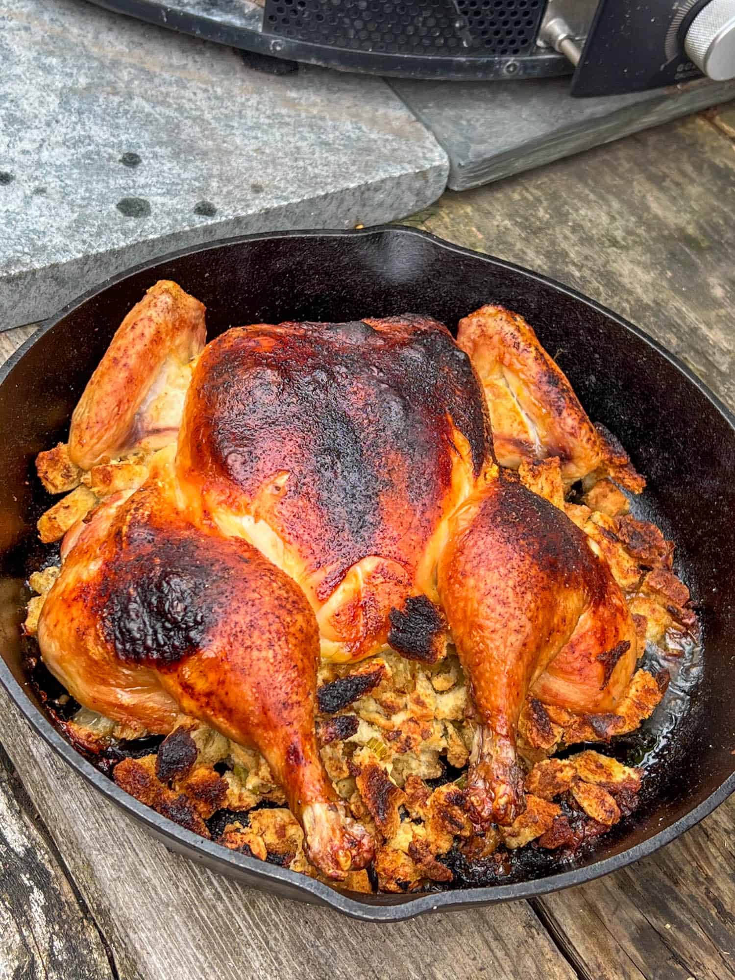 A whole chicken with stuffing roasted in a cast iron pan in a wood fired oven.