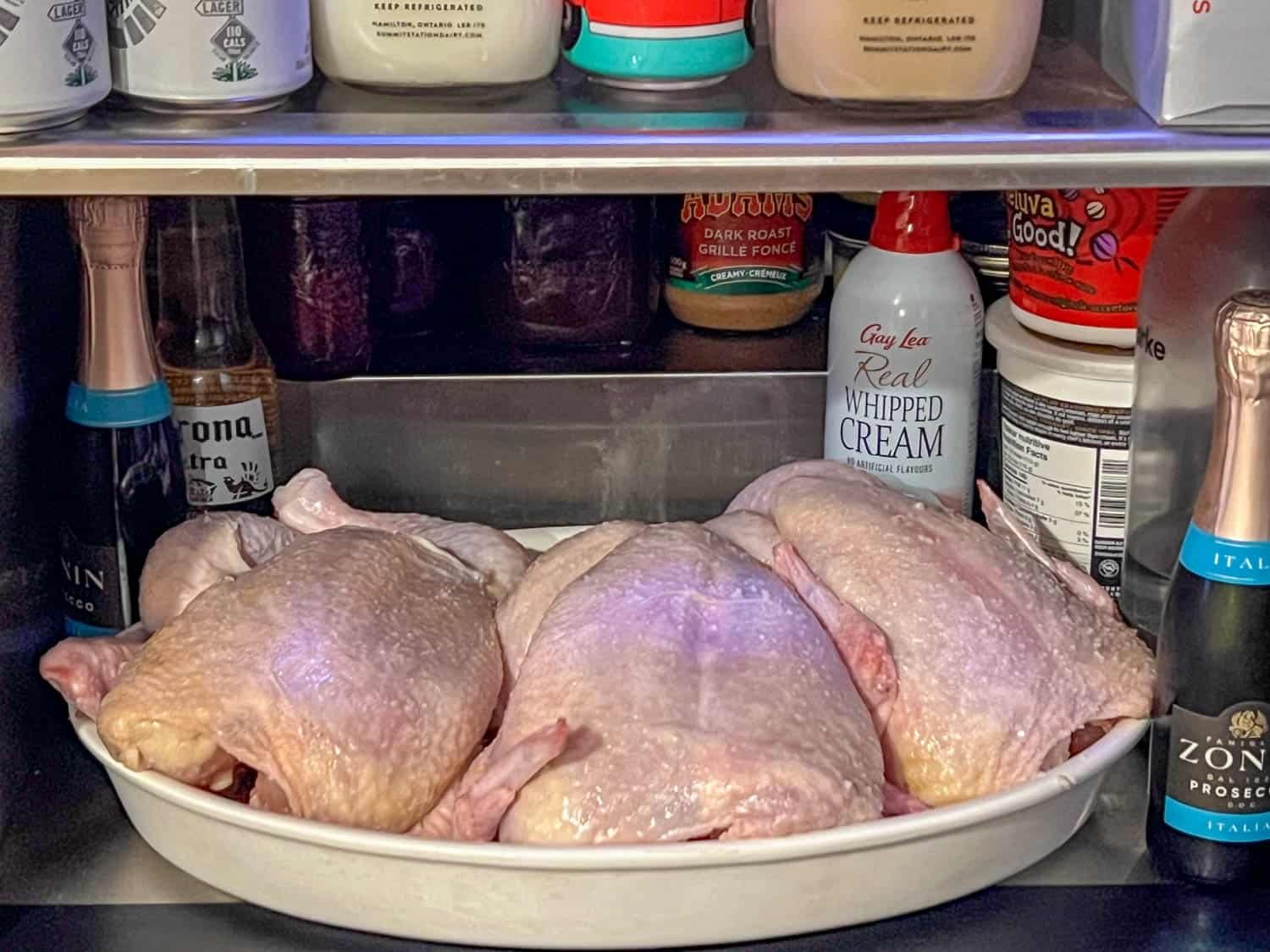 3 chickens dry brining in the fridge on an ironstone platter.