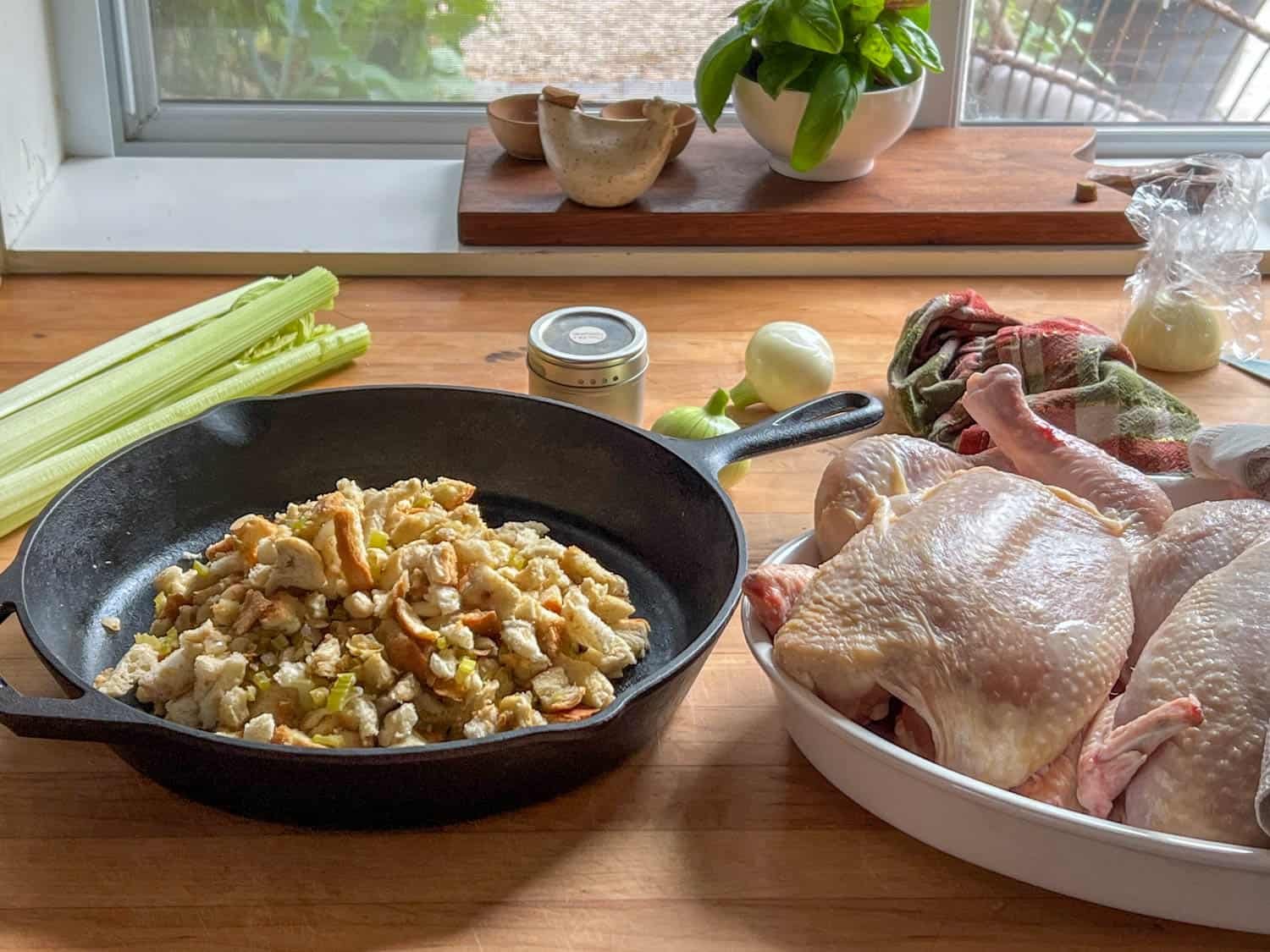 A cast iron pan mounded with stuff, and ready to roast chickens off to the side.