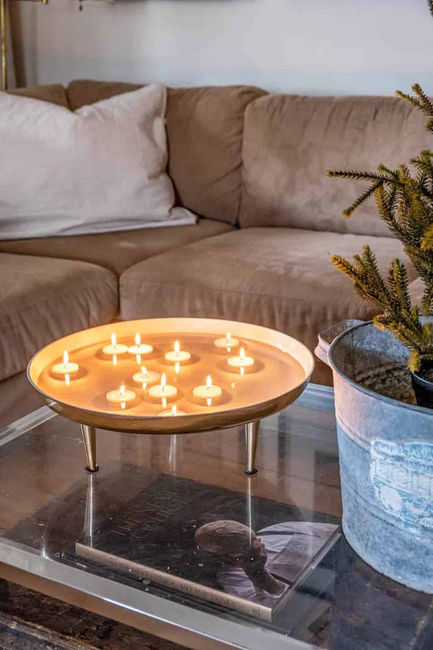 Floating tea lights lit in a shallow modern bowl on a lucite coffee table.
