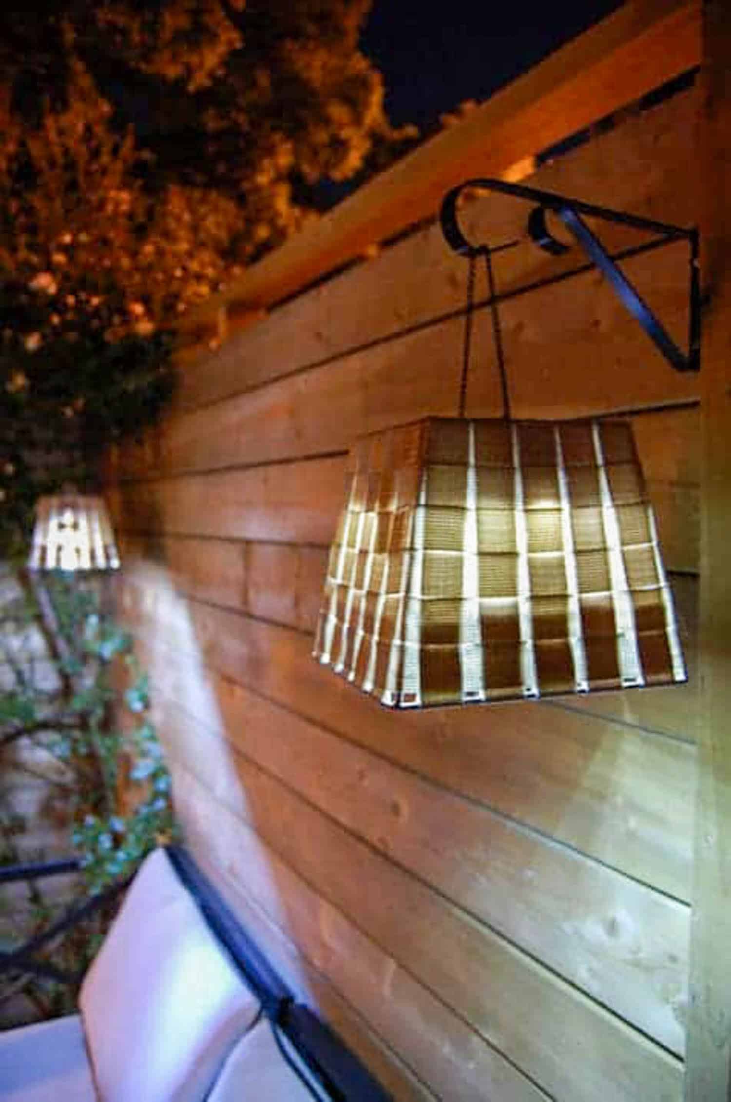 Dollar store hack of a basket being used as an outdoor lantern on a wood fence.