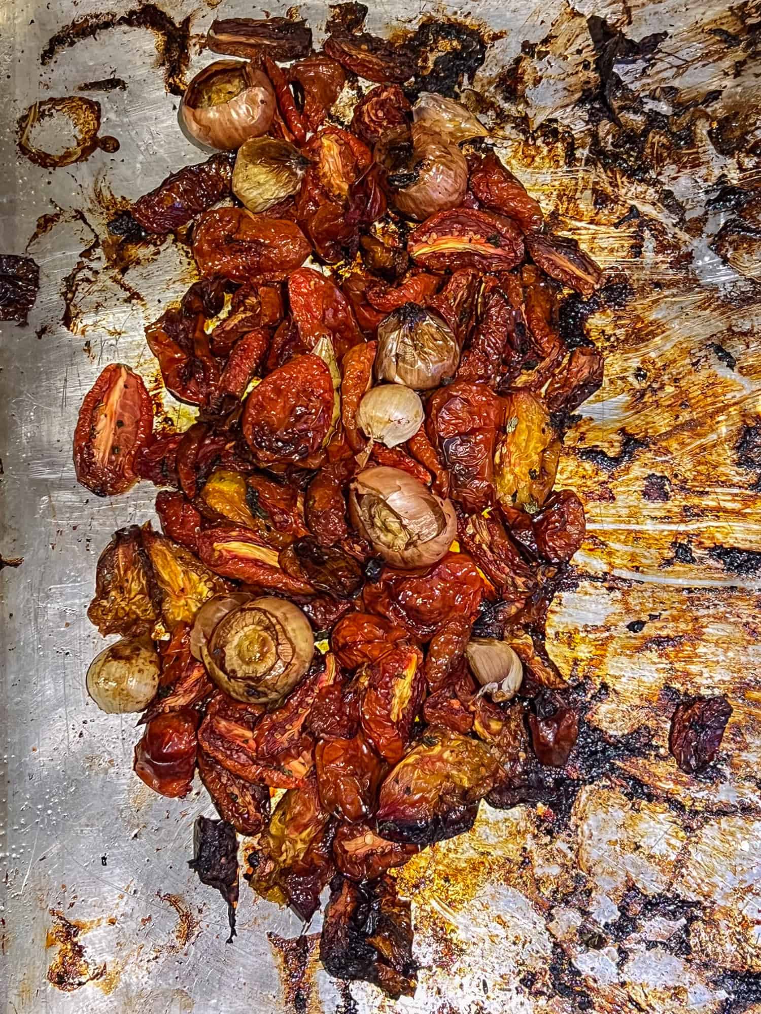 Roasted tomatoes on a sheet pan just out of the oven.