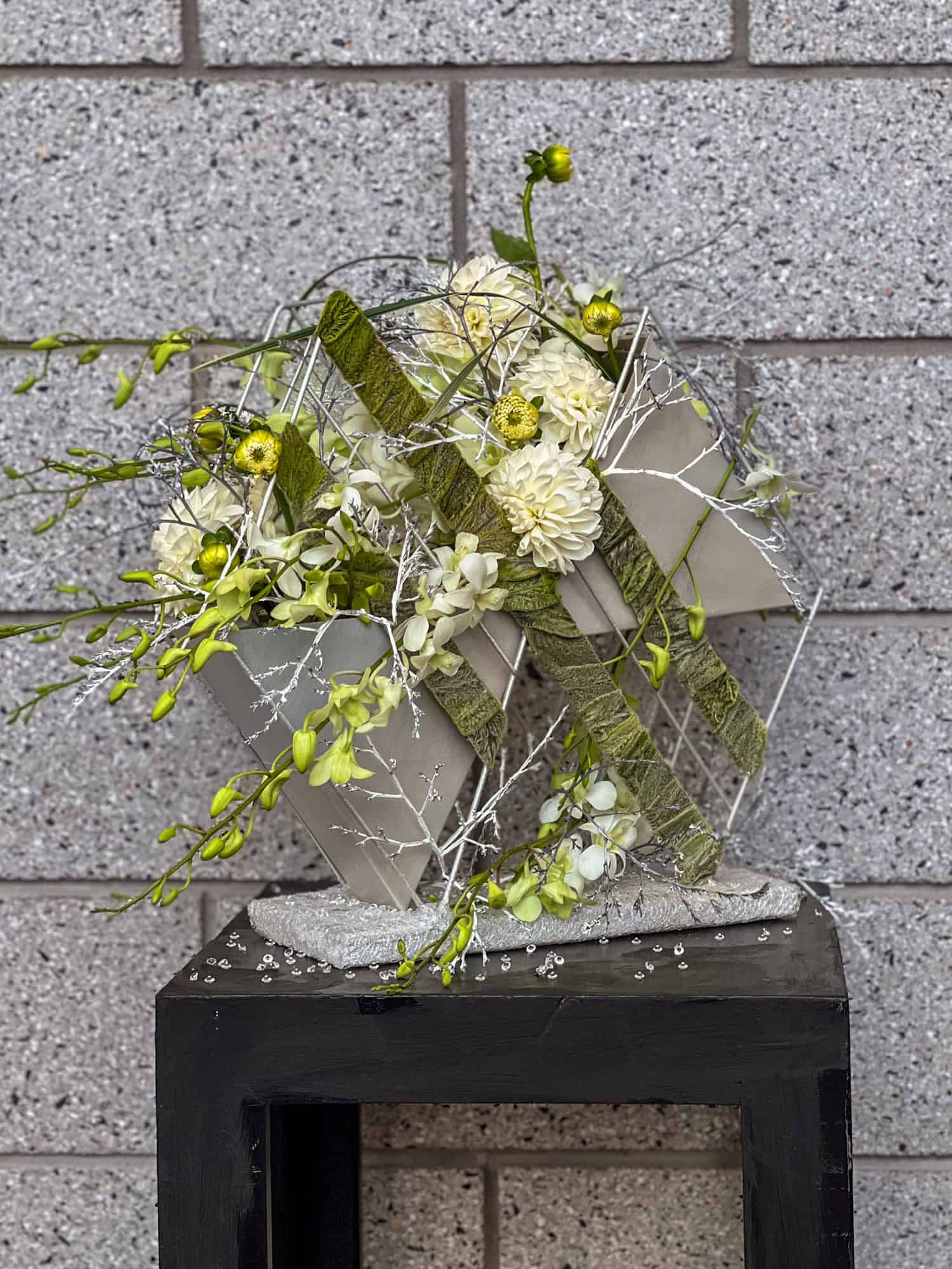 Structured, exhibition flower arrangement in white with branches.