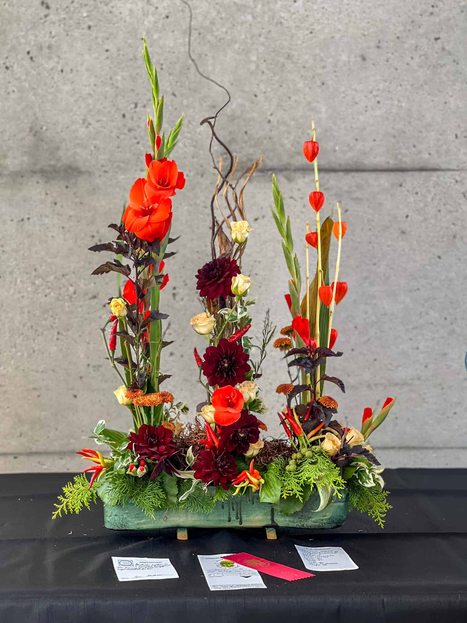 An exhibition floral arrangement with dahlias, roses, gladioli and greenery representing flames.